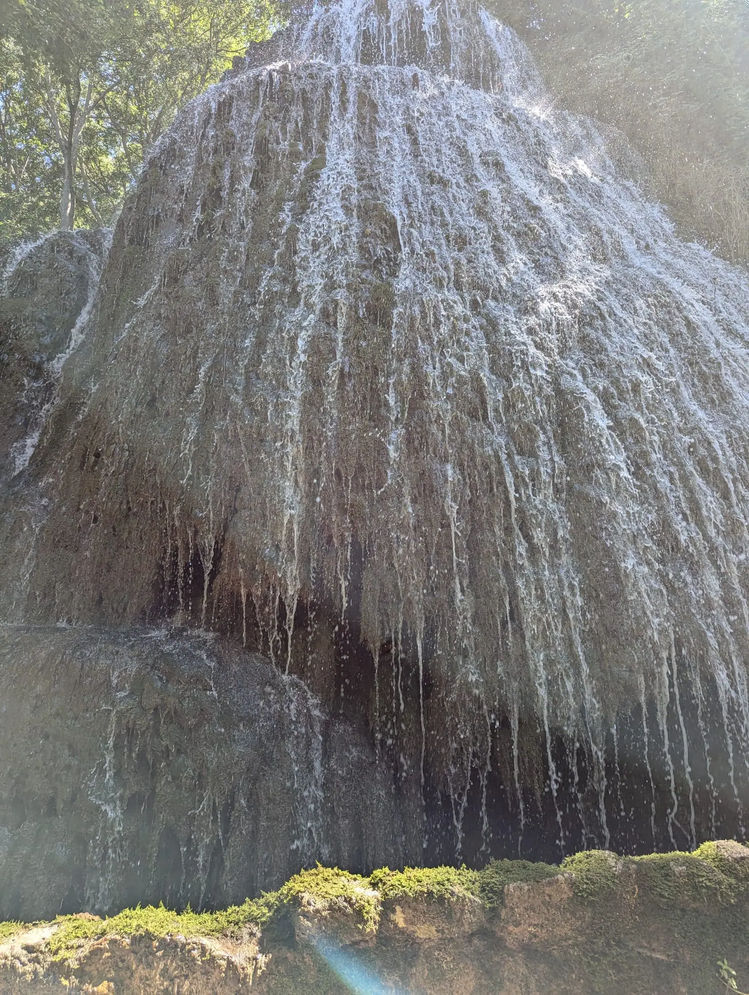 A curtain-like waterfall falling over mossy rock at Monasterio de Piedra