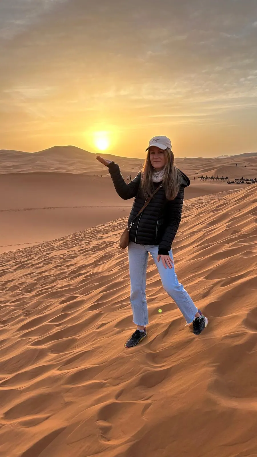 A traveler standing on Sahara sand dunes at sunset in Morocco
