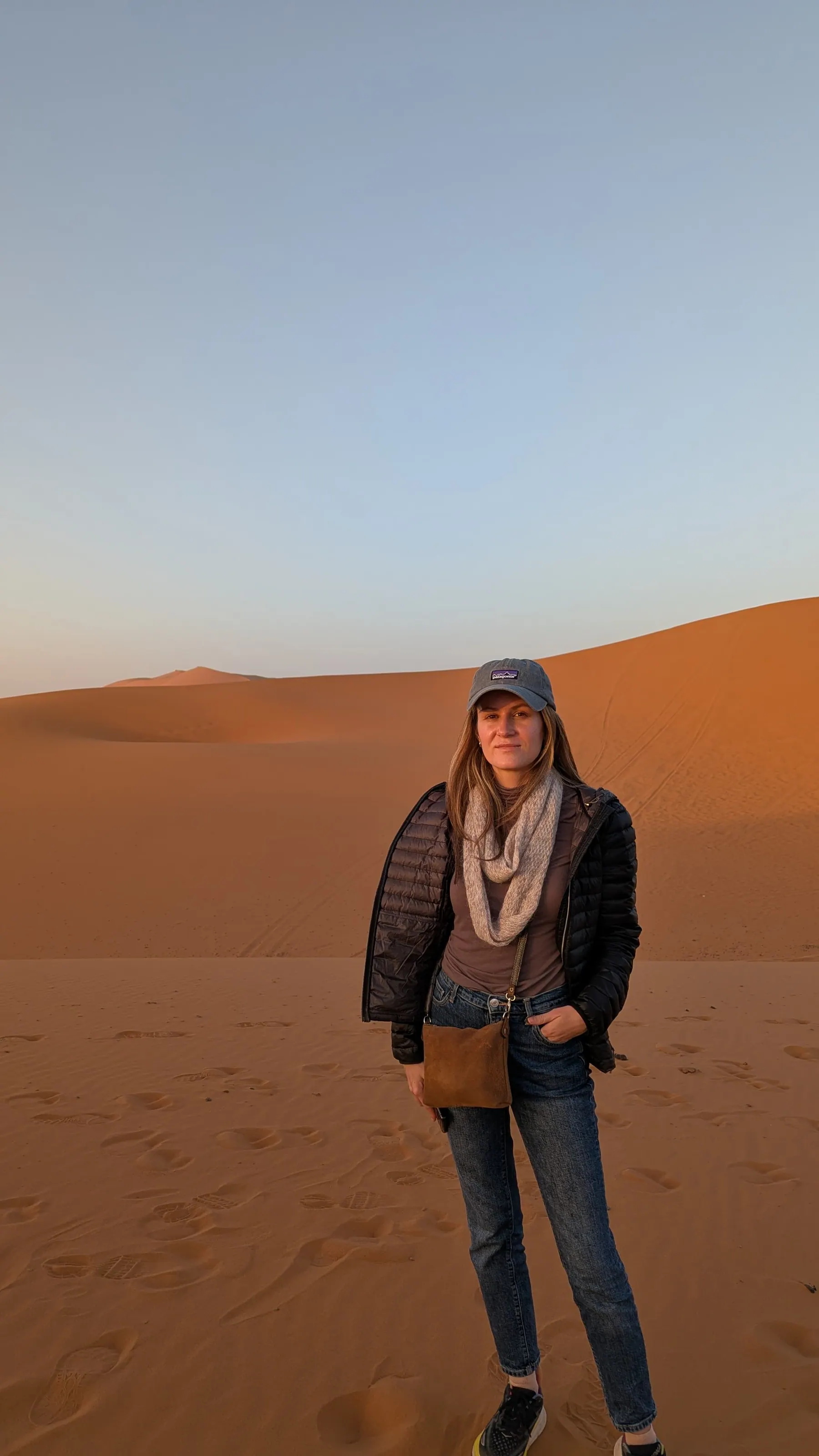 A traveler standing on orange Sahara dunes in Morocco