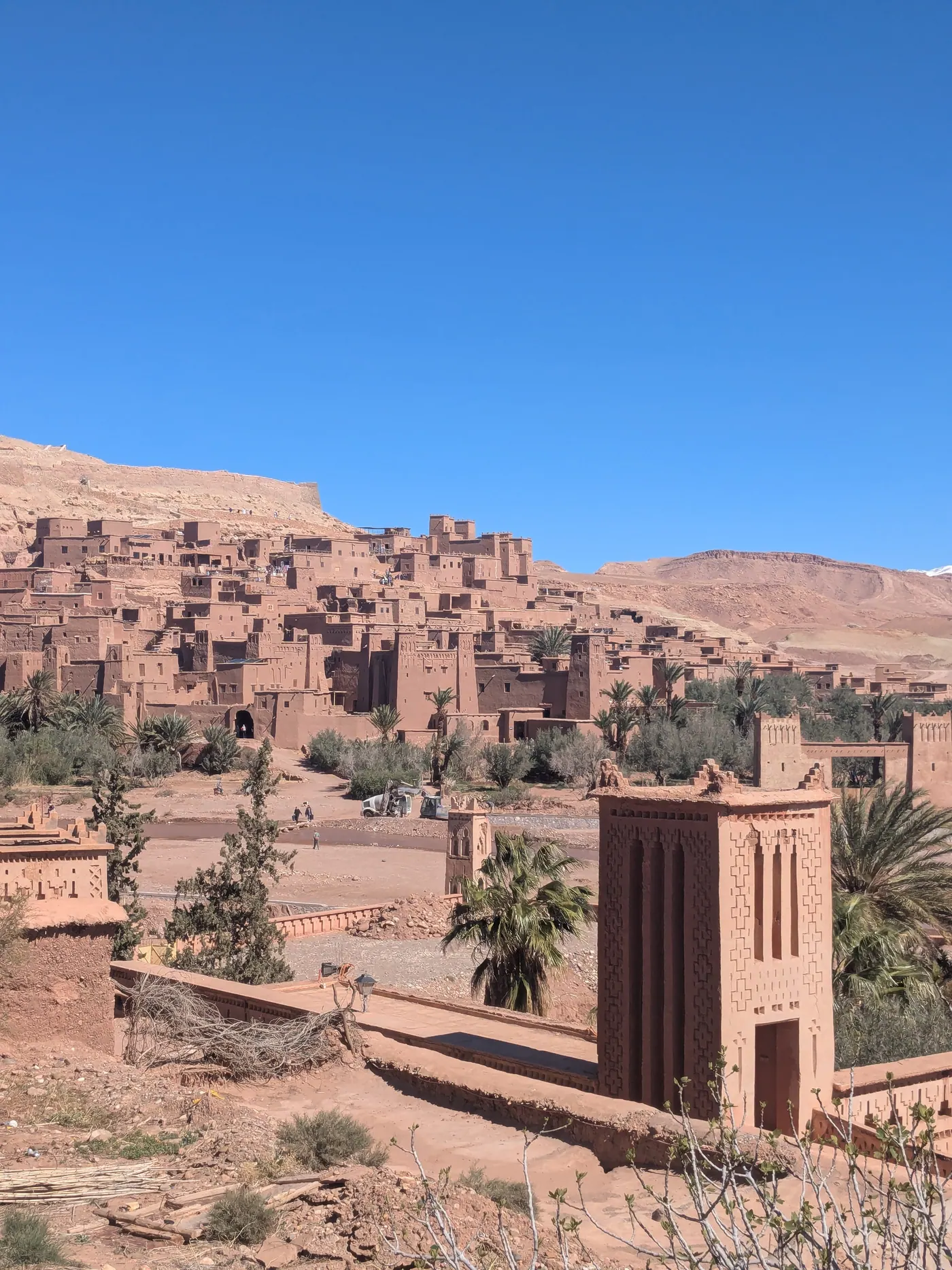 Ait Benhaddou earthen village surrounded by dry hills and palm trees in Morocco
