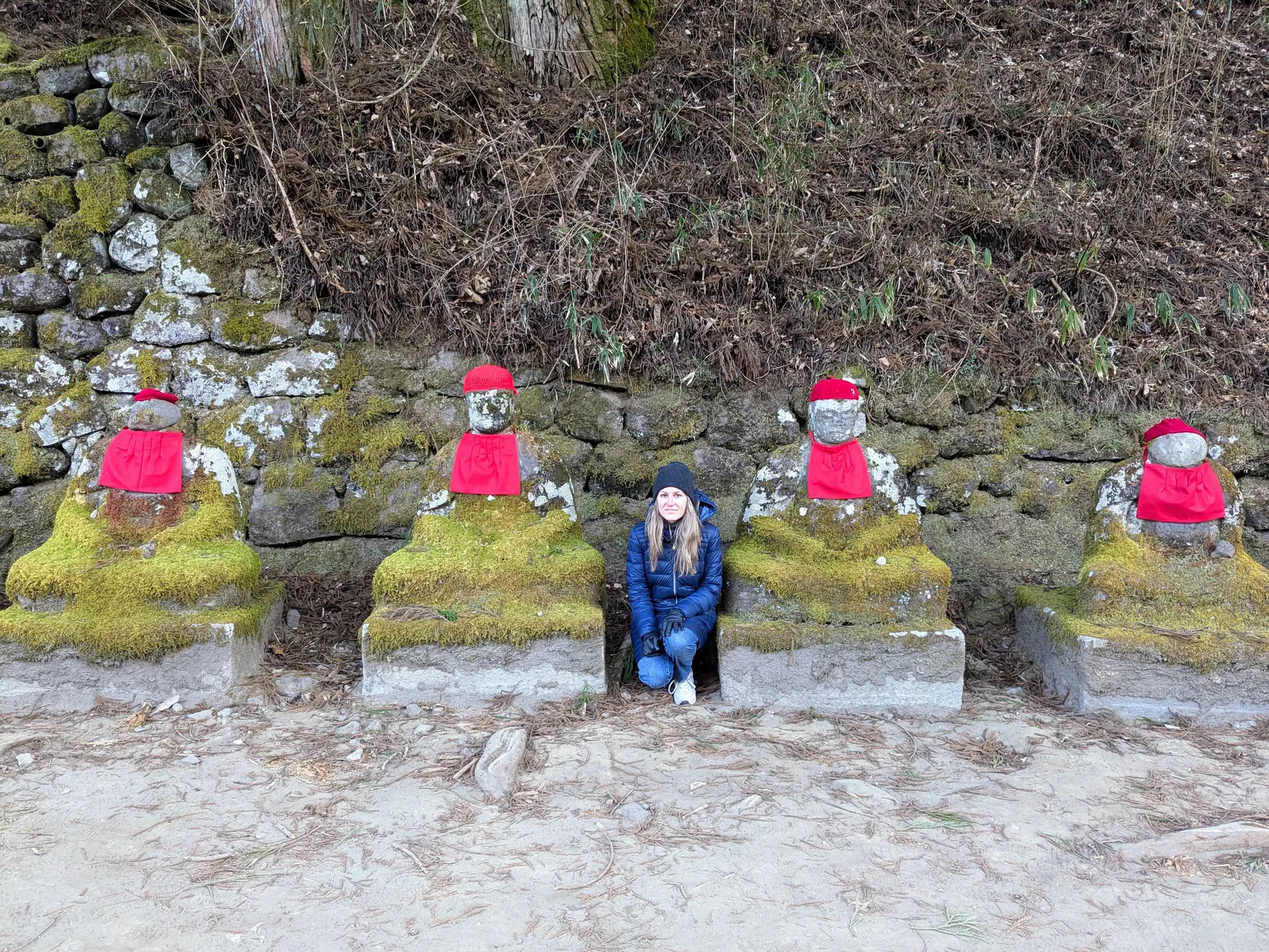 Rows of red-capped Jizō statues beside the trail in Nikko