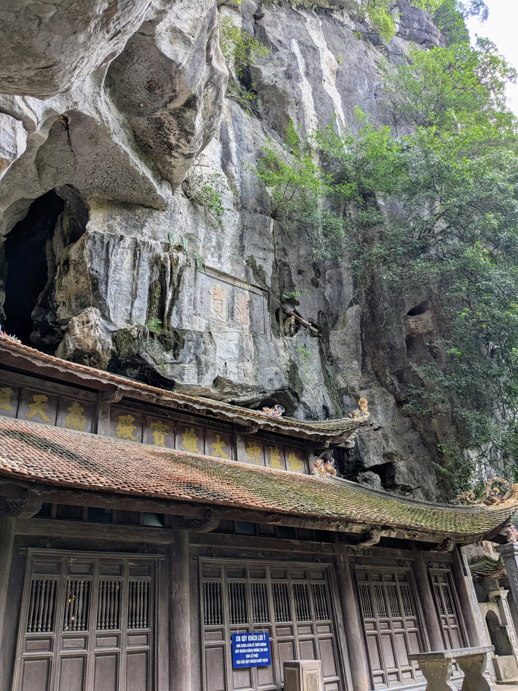 The weathered facade of a temple built against the limestone cliff at Bich Dong