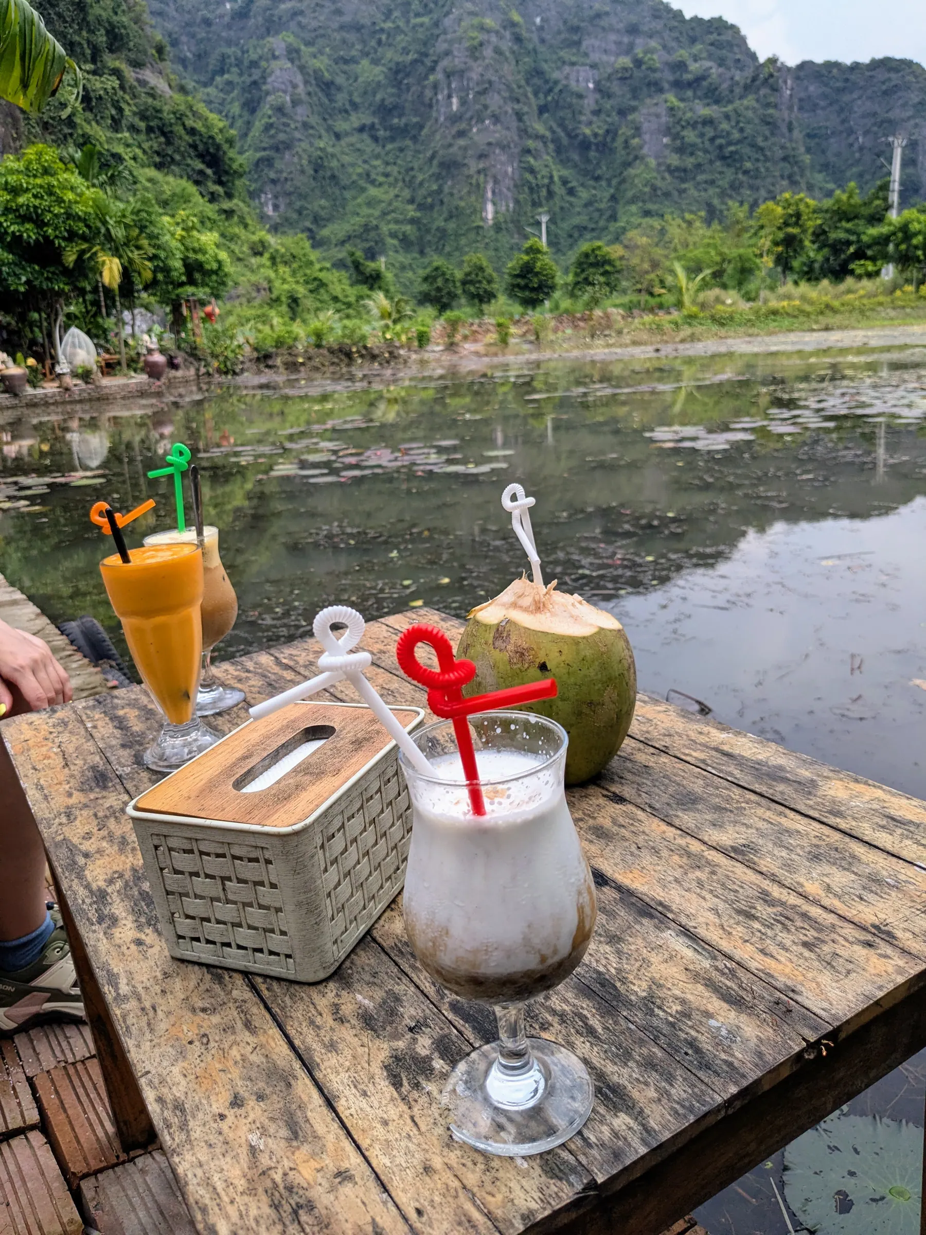 Coconut coffee and drinks on a wooden table beside a pond
