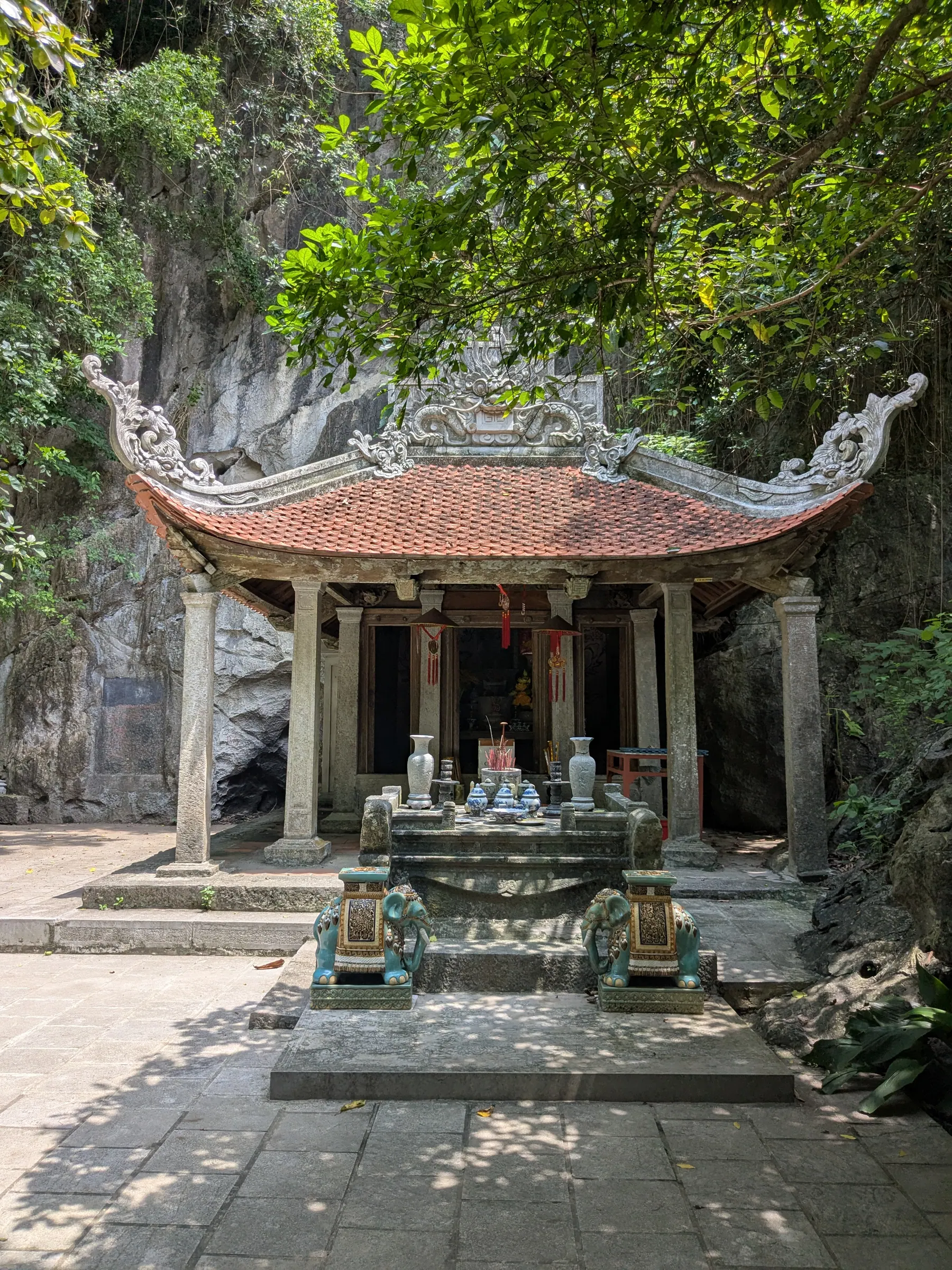 A small shrine beneath a curved roof surrounded by tropical trees