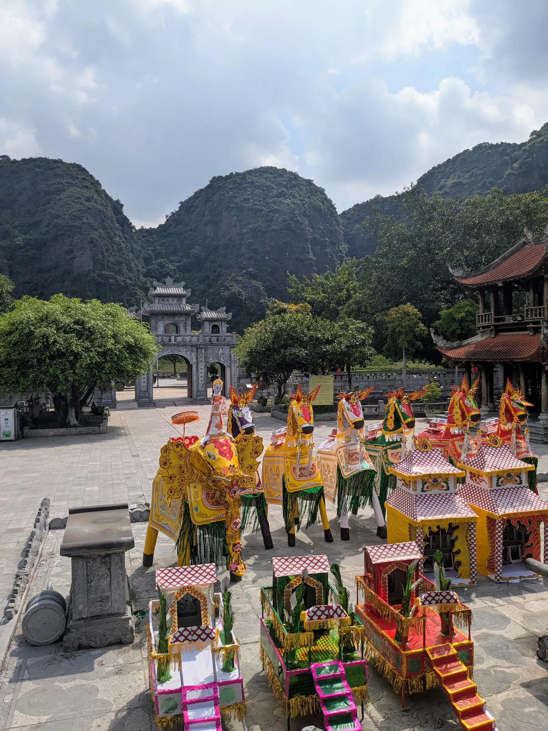 Bright votive horses and offerings arranged outside Den Thai Vi