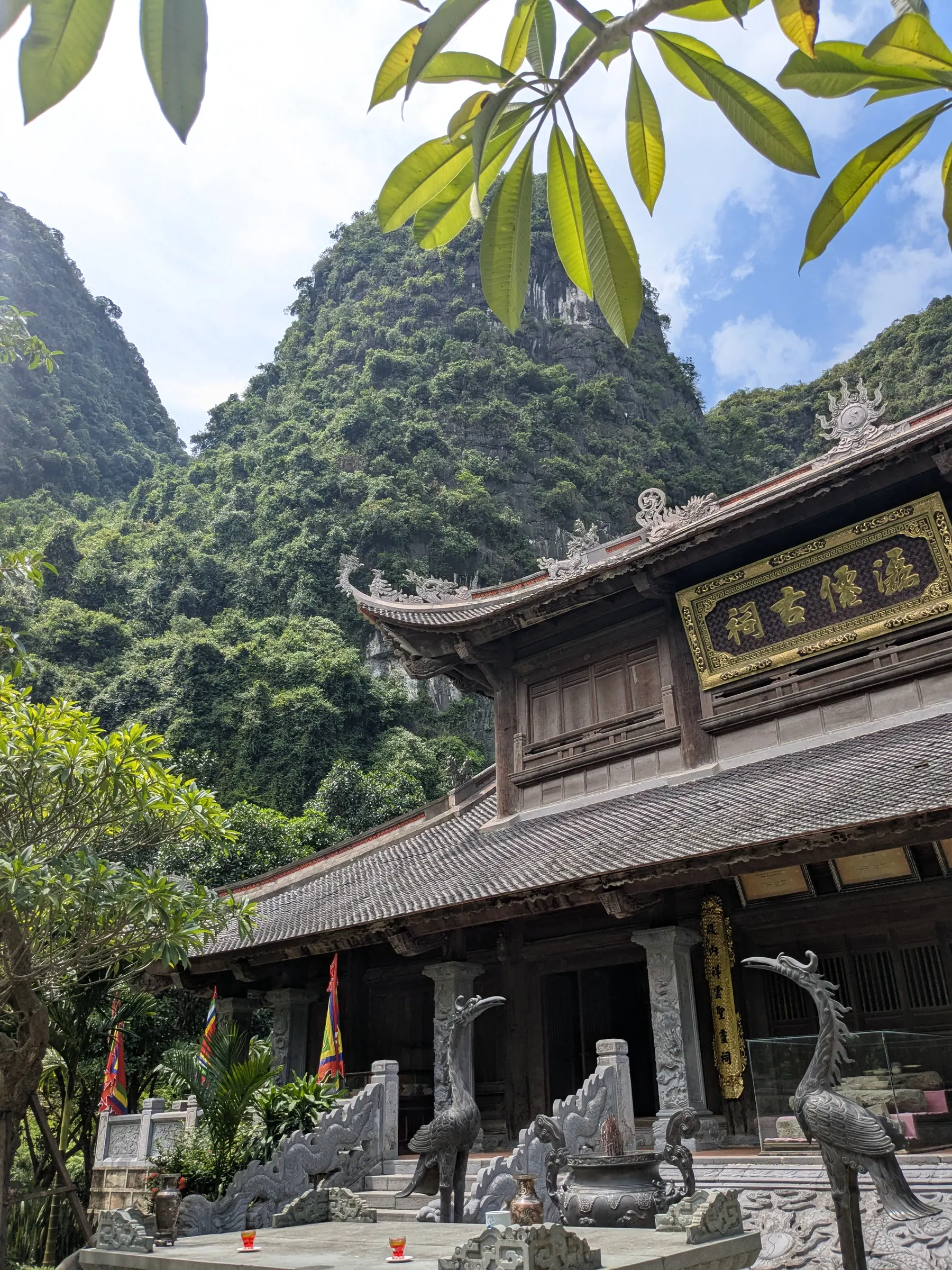 A temple roof and limestone karsts viewed through tropical trees