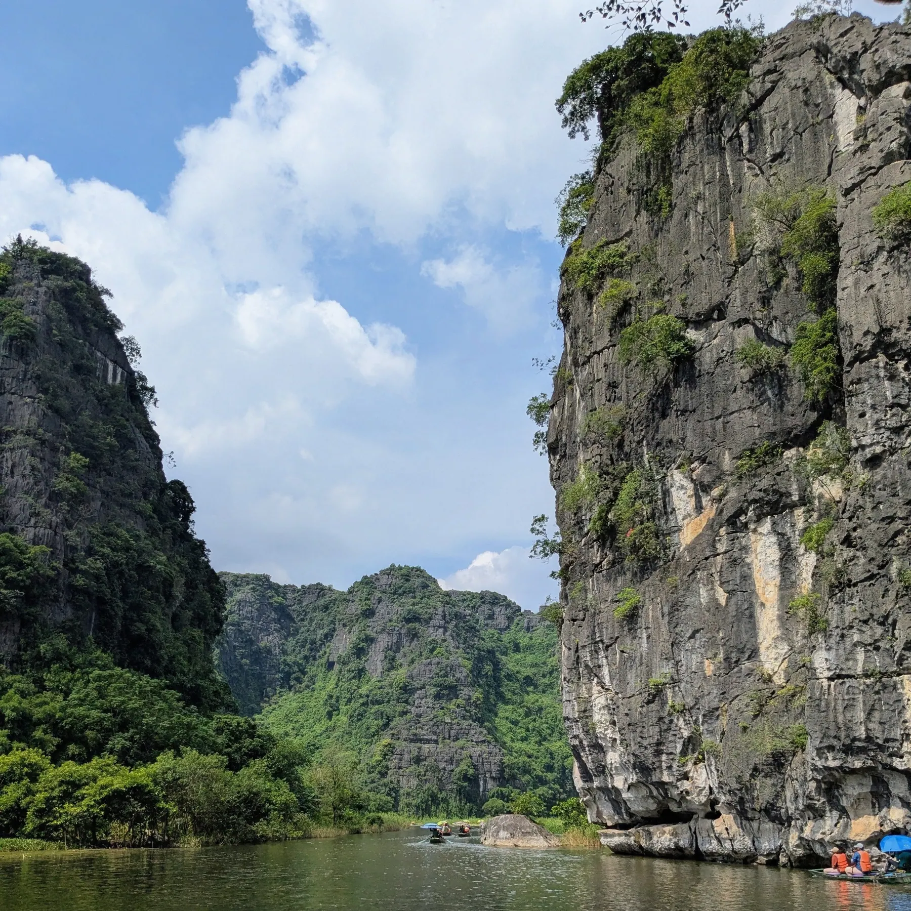 Towering limestone cliffs above the water with small tour boats in Ninh Binh