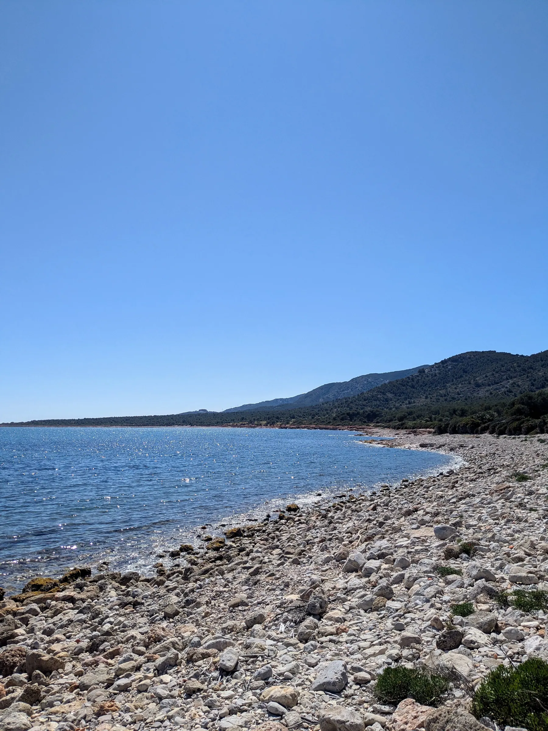 Quiet pebble beach and low hills at Platja del Barranc d'Irta