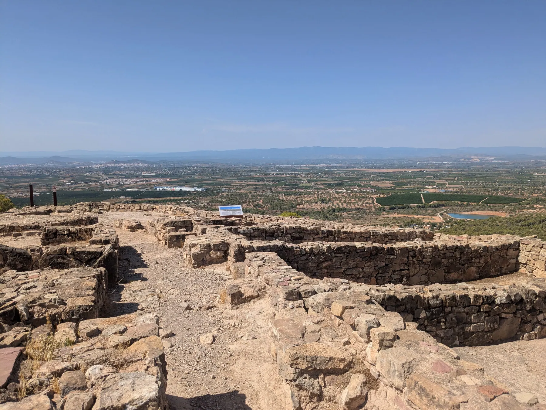 Low stone foundations at Puntal dels Llops with the Valencian plain beyond