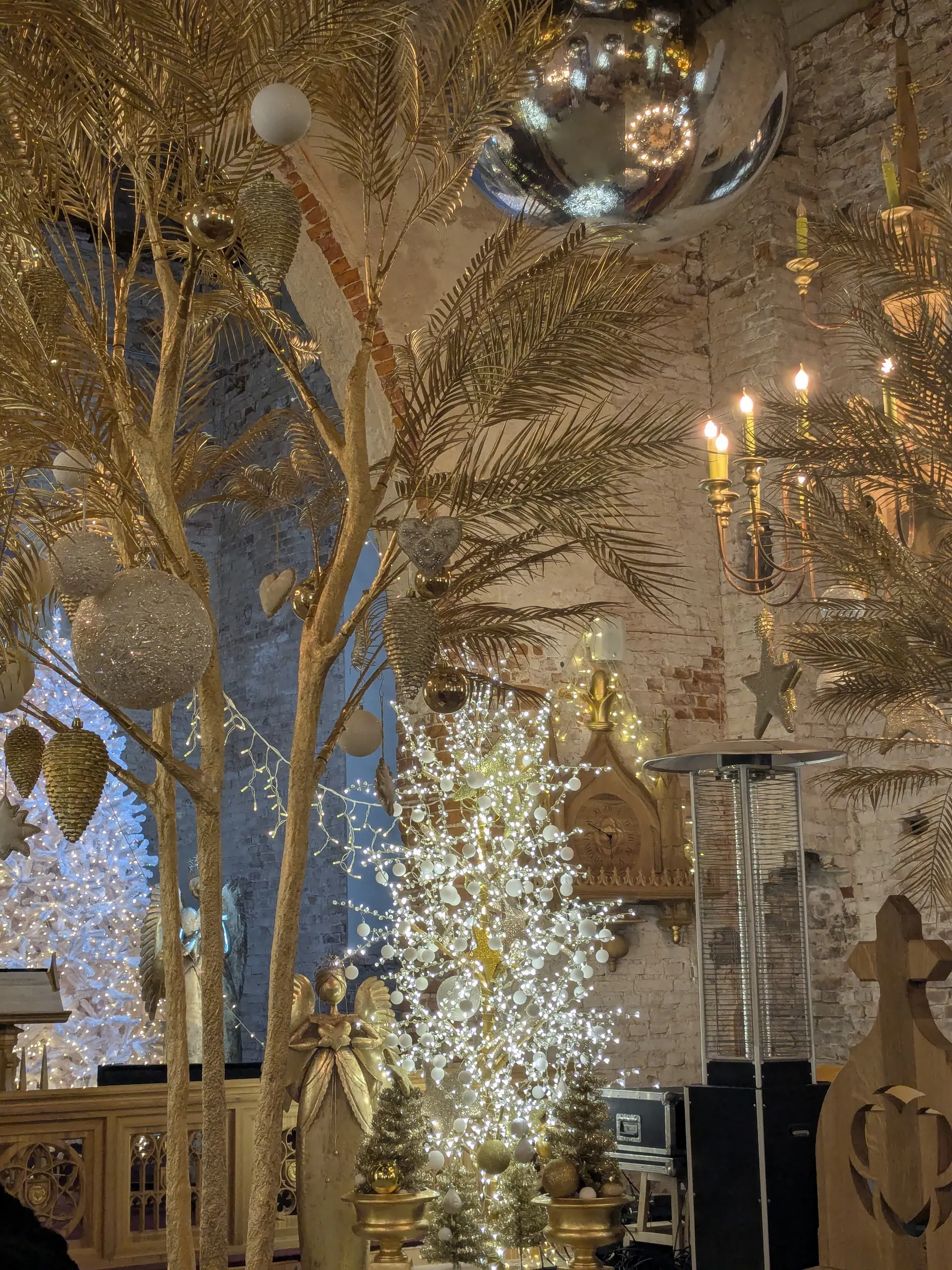 Interior detail of Ropaži Church with golden palm-style trees, giant mirror spheres, and candlelight chandeliers