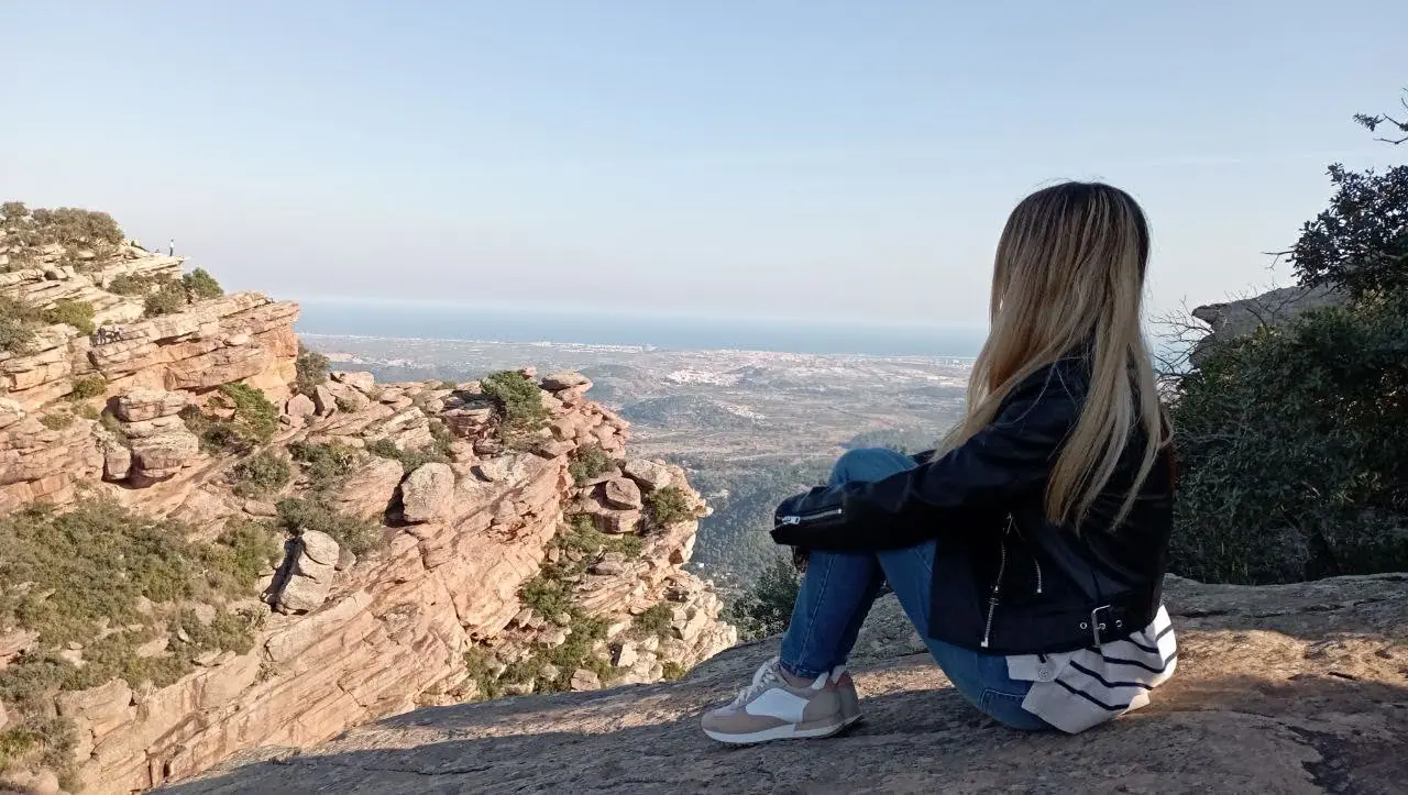 Una viajera sentada en el borde de arenisca roja del Mirador del Garbí