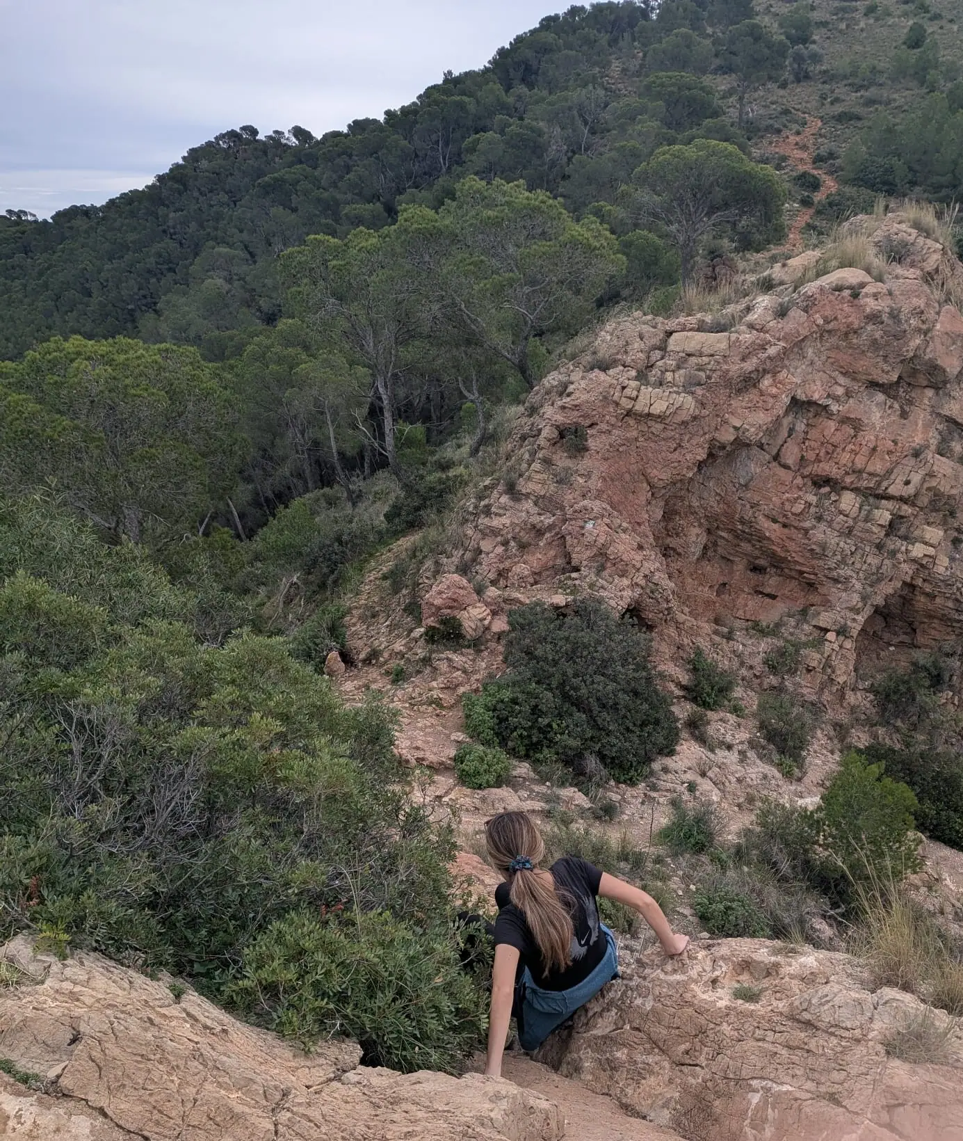 Una senderista subiendo la última ladera rocosa hacia La Creueta sobre Náquera