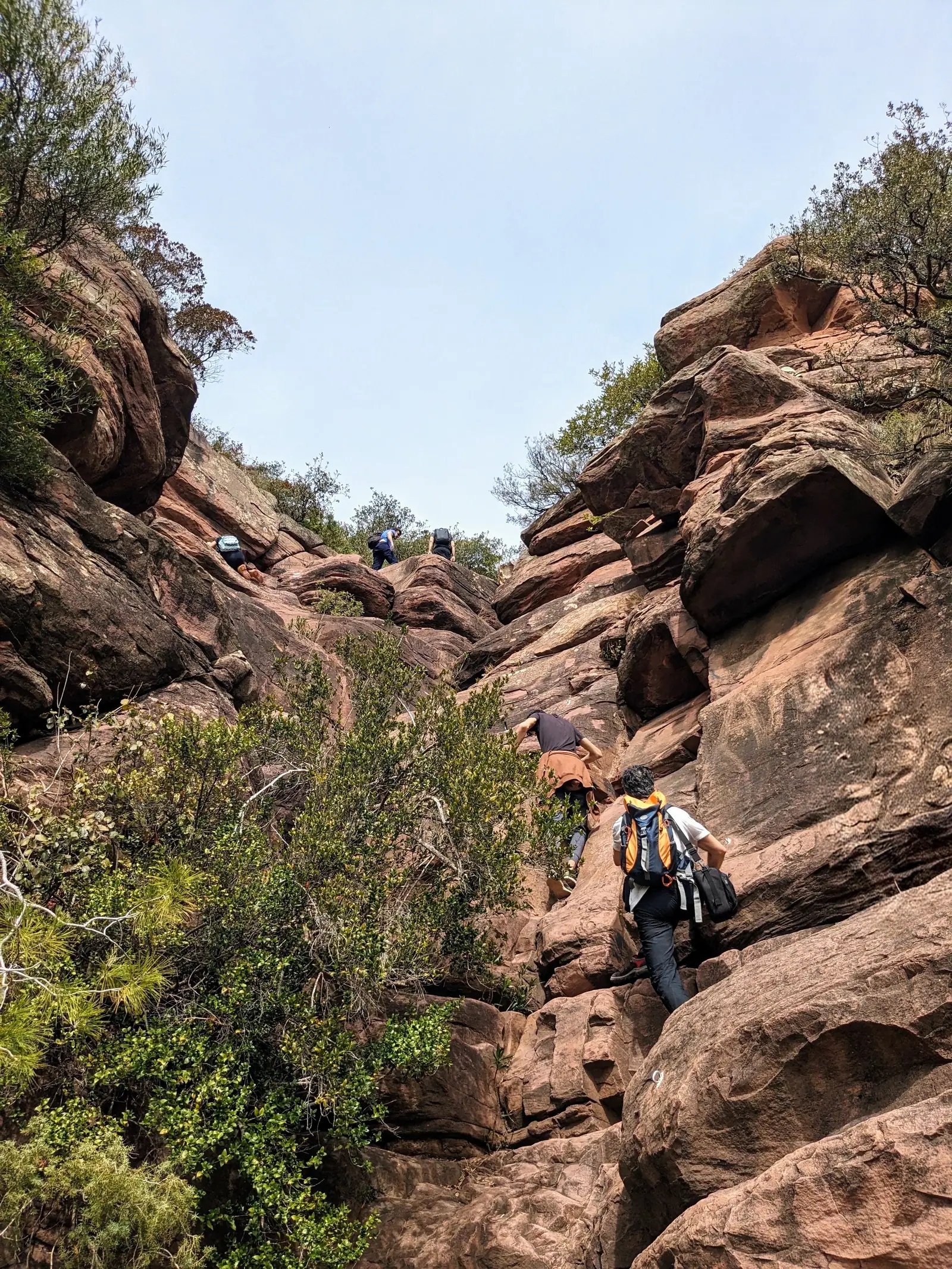 Una senderista subiendo entre la roca roja de la Ruta de les Cadenes