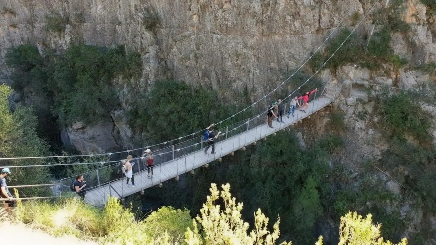 Steel suspension footbridge hanging high across the sheer limestone cliffs of the Turia canyon