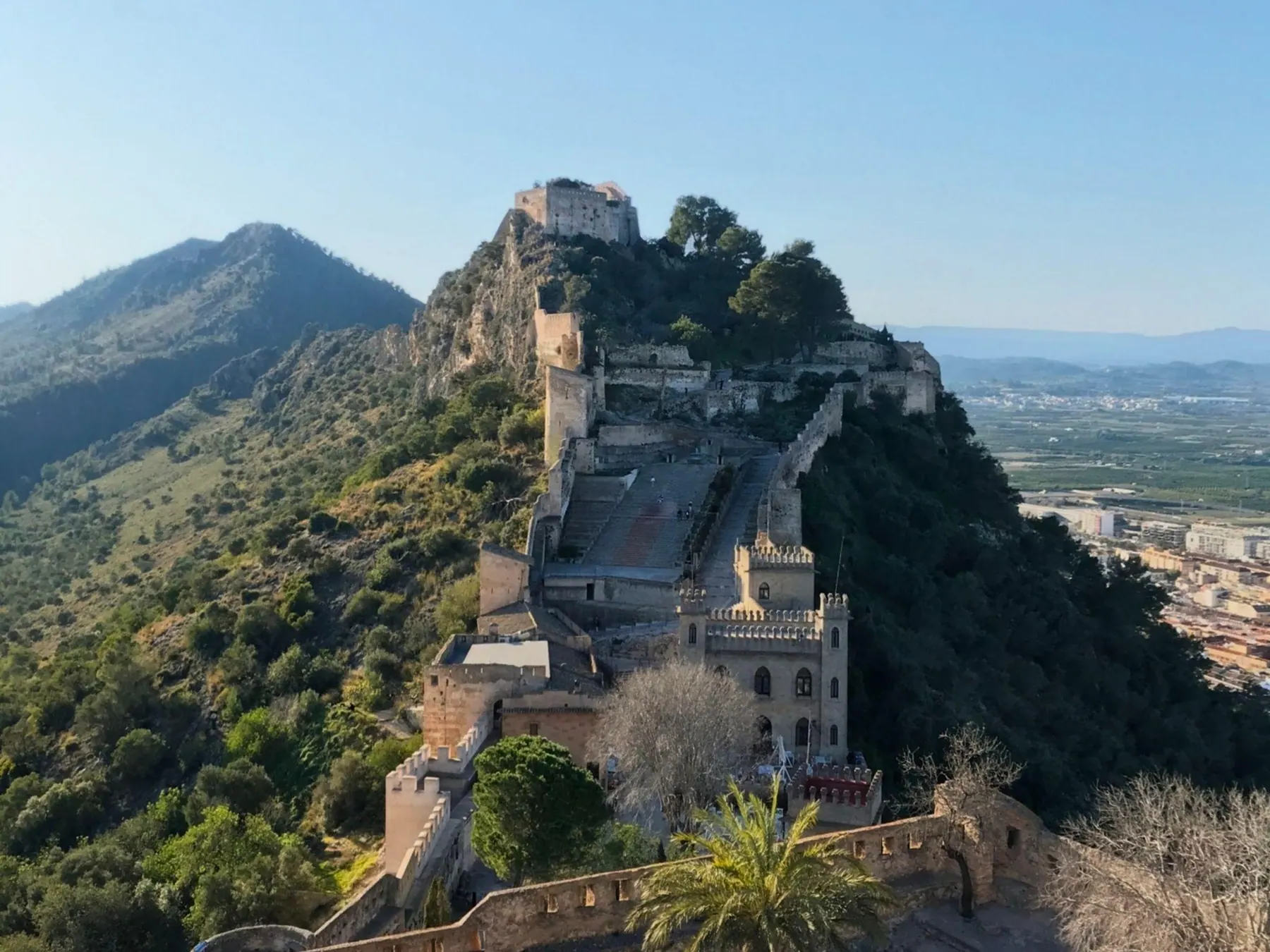 Panoramic view of the stone walls and fortified towers of Xàtiva Castle along the mountain ridge
