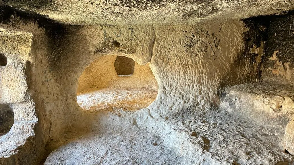 Dozens of rectangular window chambers carved high into the sheer vertical cliff of Covetes dels Moros