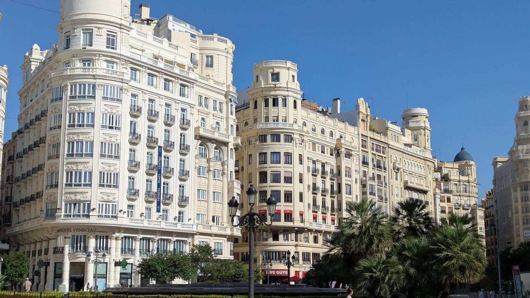 Edificios señoriales y palmeras en la explanada de la Plaza del Ayuntamiento bajo la luz del día