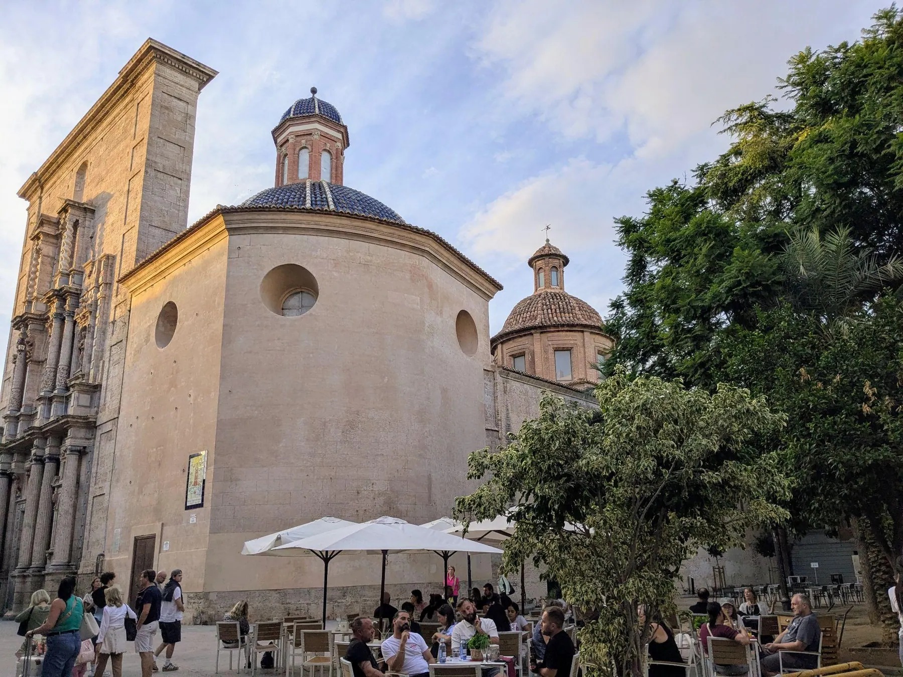 Plaza del Carmen con la cúpula de la iglesia, terrazas de cafetería a la sombra y árboles frondosos