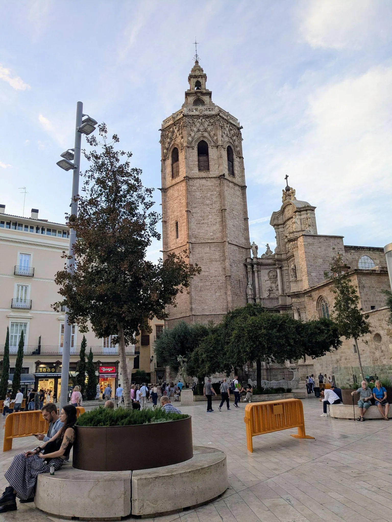 Paseo peatonal y palmeras en la Plaza de la Reina con el campanario de la Catedral al fondo