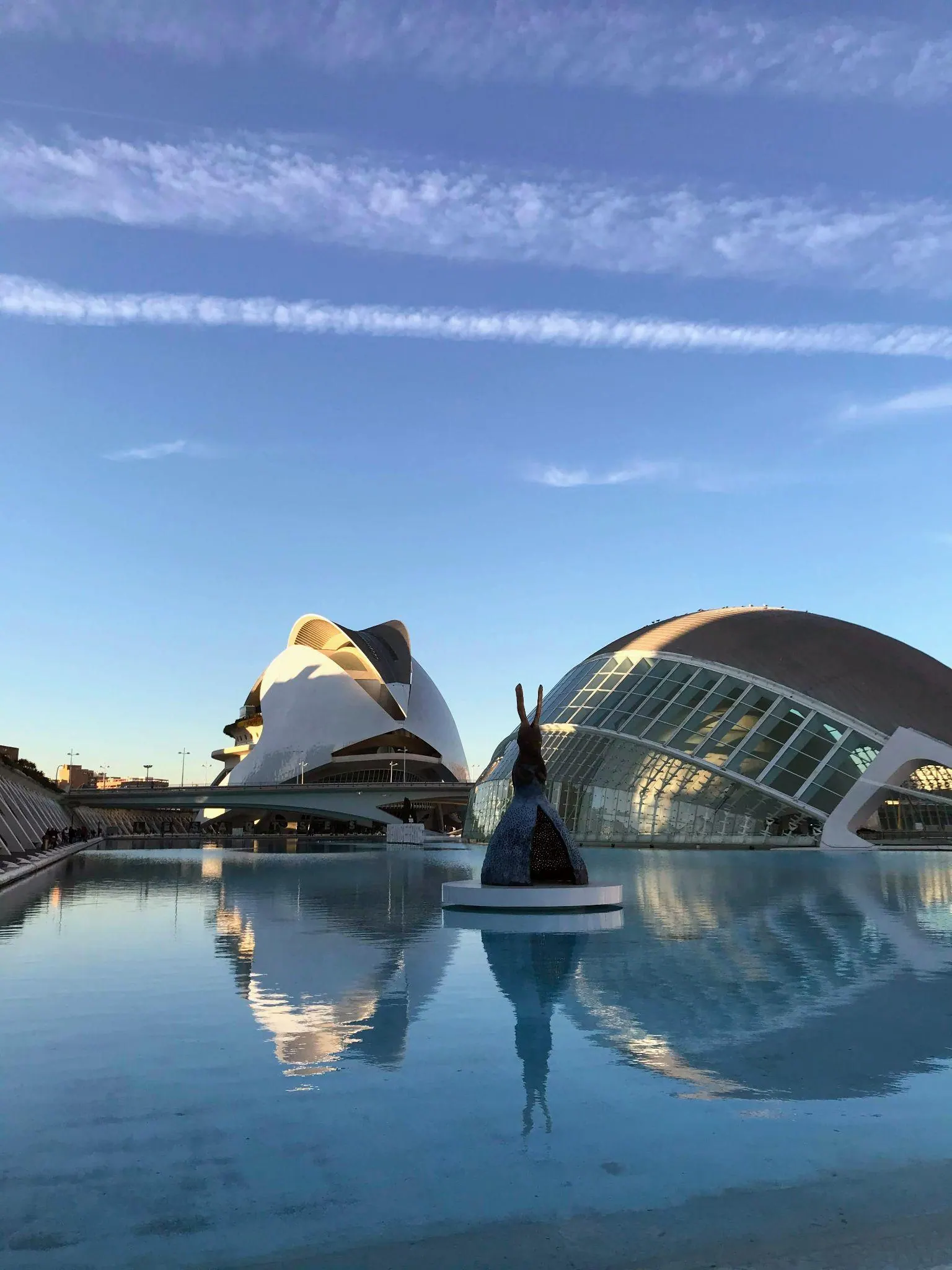 Arquitectura vanguardista blanca y pasarelas peatonales reflejadas en las láminas de agua de la Ciudad de las Artes y las Ciencias
