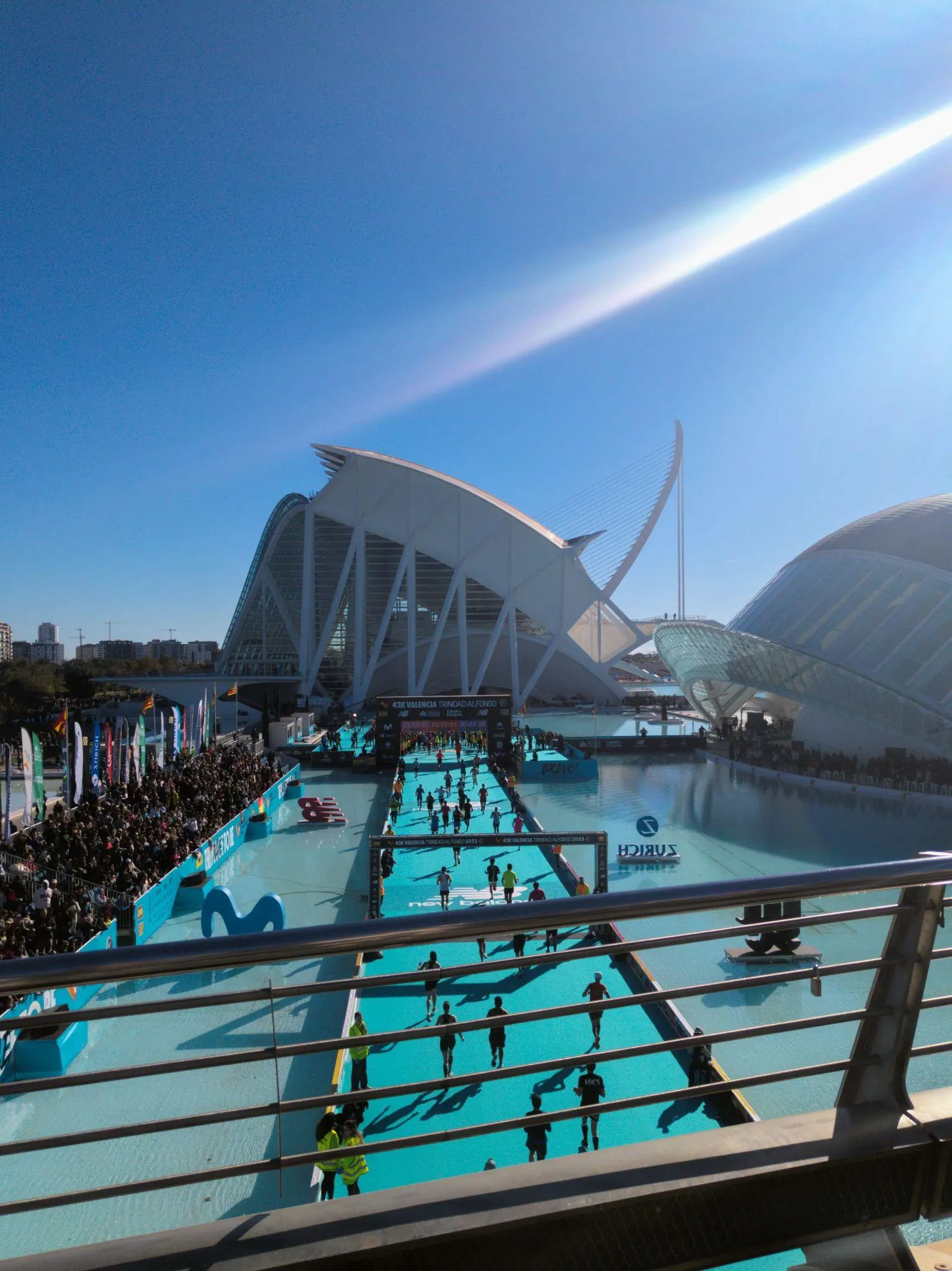 Corredores participando en la maratón cruzando las pasarelas sobre el agua en la Ciudad de las Artes y las Ciencias
