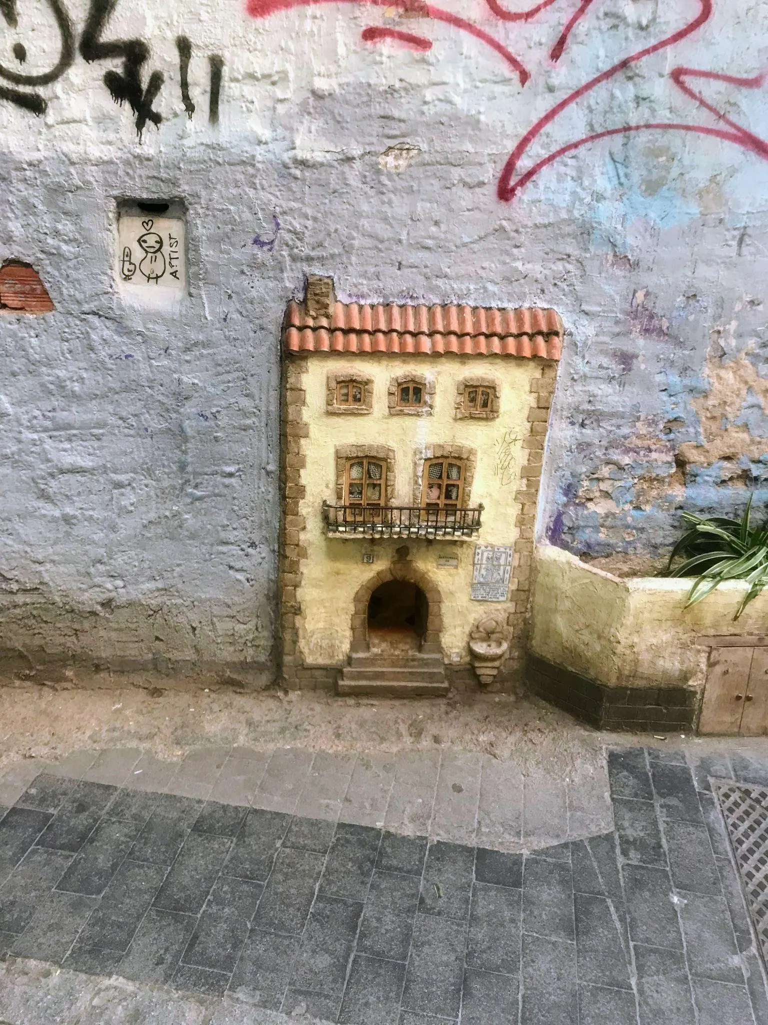 Fachada en miniatura de piedra y gatera de la Casa dels Gats en la calle del Museo