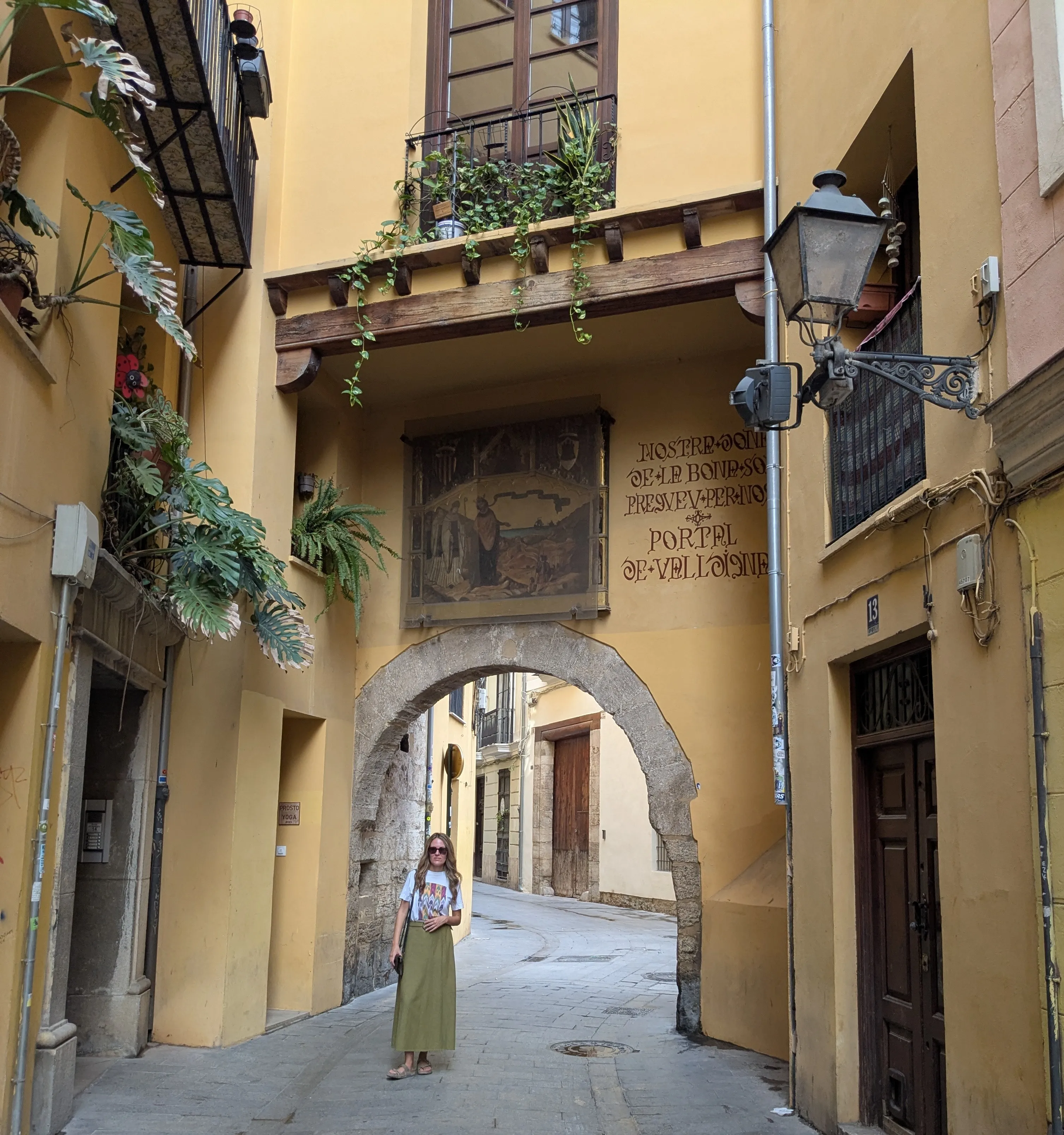 Arco gótico de piedra del Portal de Valldigna con inscripción medieval y viajera bajo el portal