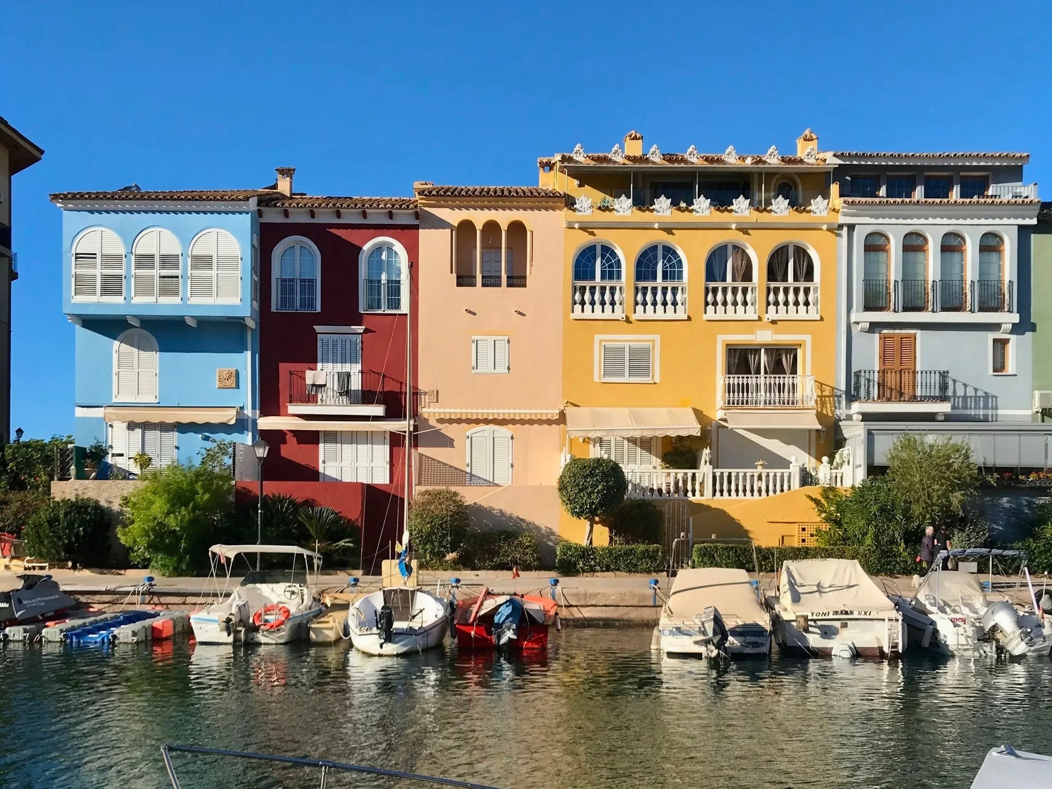 Hilera de casas de colores en tonos pastel y barcos amarrados a lo largo del canal del puerto de Port Saplaya