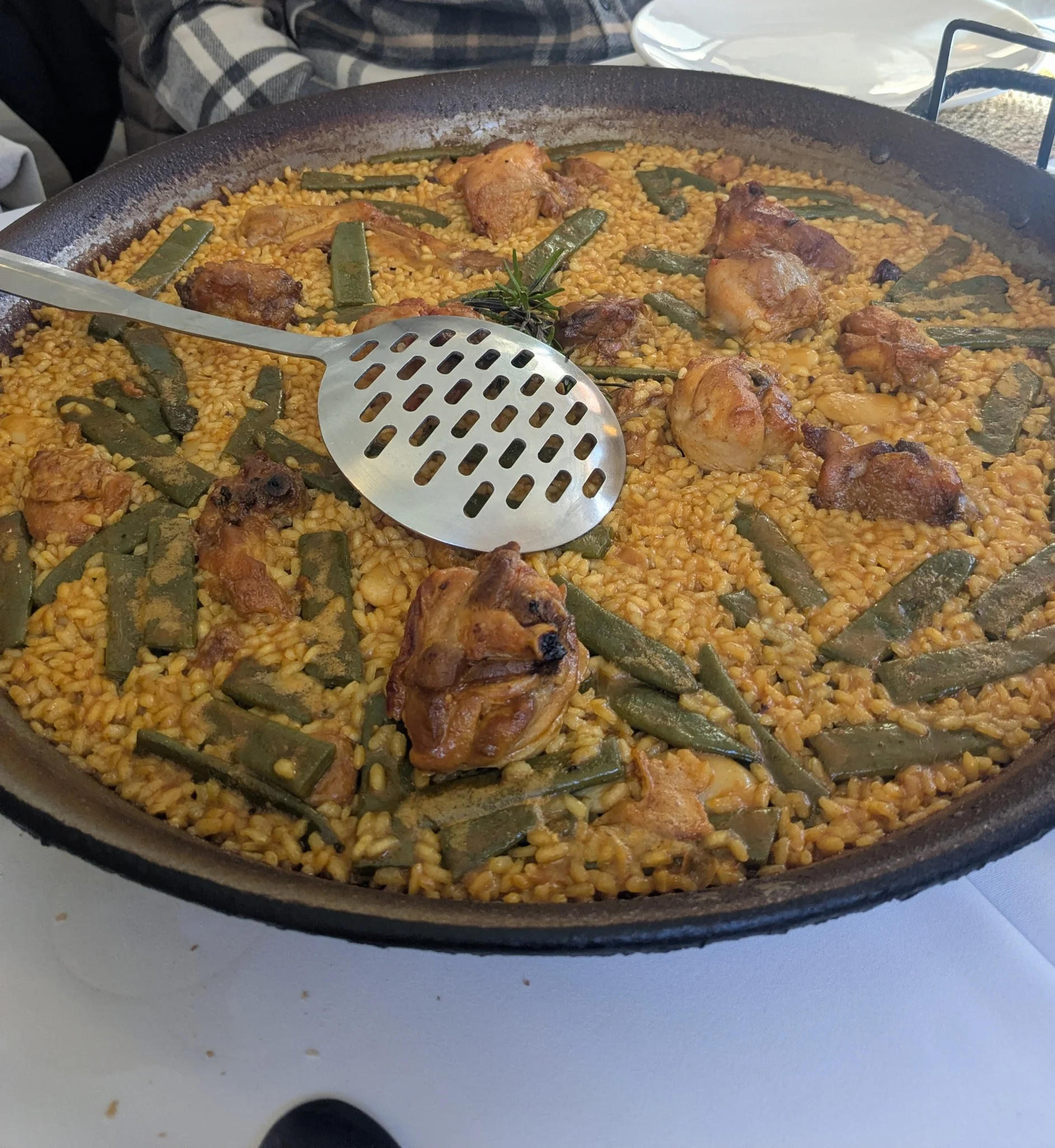 Paella valenciana tradicional servida en paella de hierro con pollo, romero, bajoqueta y alubias garrofó